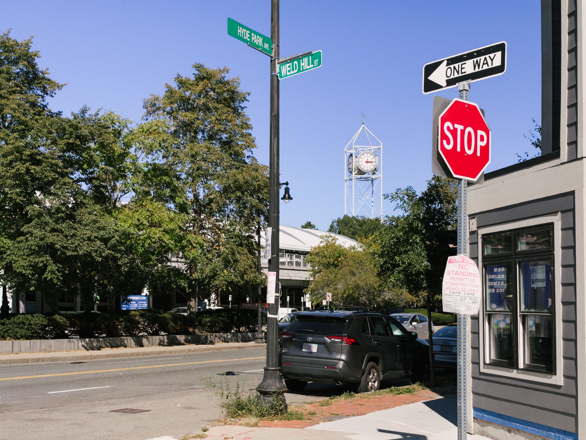 Construction parking notices at Hyde Park Avenue and Weld Hill Street, with the Forest Hills clock tower behind them